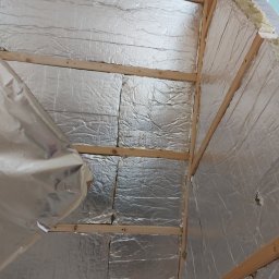 Oleksandr Turchynskyi - Izolacja termiczna z folią aluminiową i drewnianą konstrukcją szkieletową, widoczne fragmenty wełny mineralnej na styku ściany i sufitu.