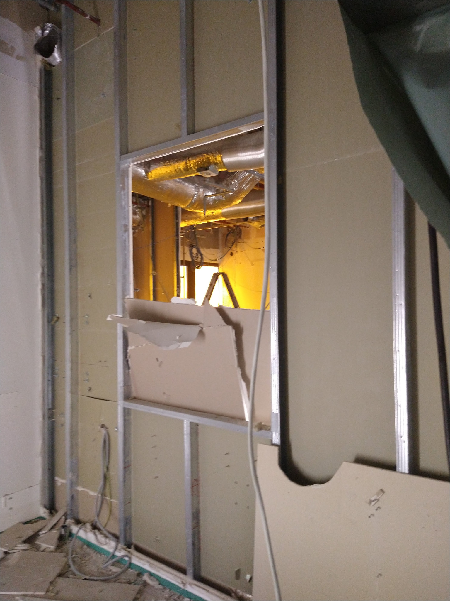 Montaż płyty karton gips w Łańcucie: widok na metalowy stelaż z częściowo zamontowaną płytą, przez otwór widać instalacje. Prace wykończeniowe w trakcie.