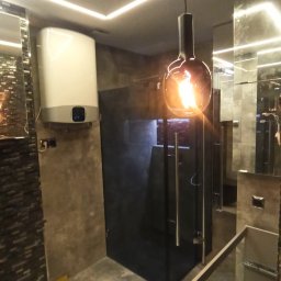 Paweł Wegner - Nowoczesna łazienka z kabiną prysznicową typu walk-in, podgrzewaczem wody na ścianie, oświetleniem LED na suficie i wiszącą lampą w stylu industrialnym.