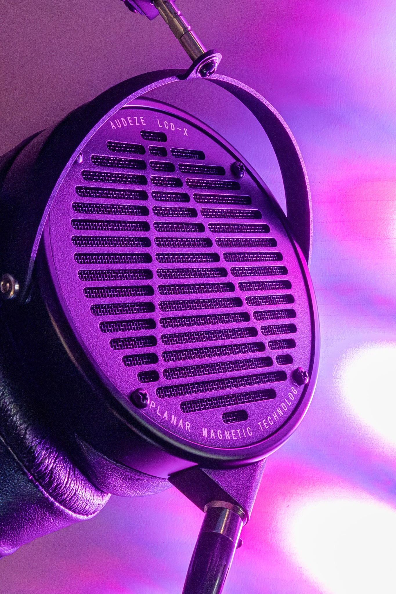 Słuchawki Audeze LCD-X z otwartą konstrukcją, oświetlone fioletowym światłem, widoczne napisy 'Planar Magnetic Technology'.