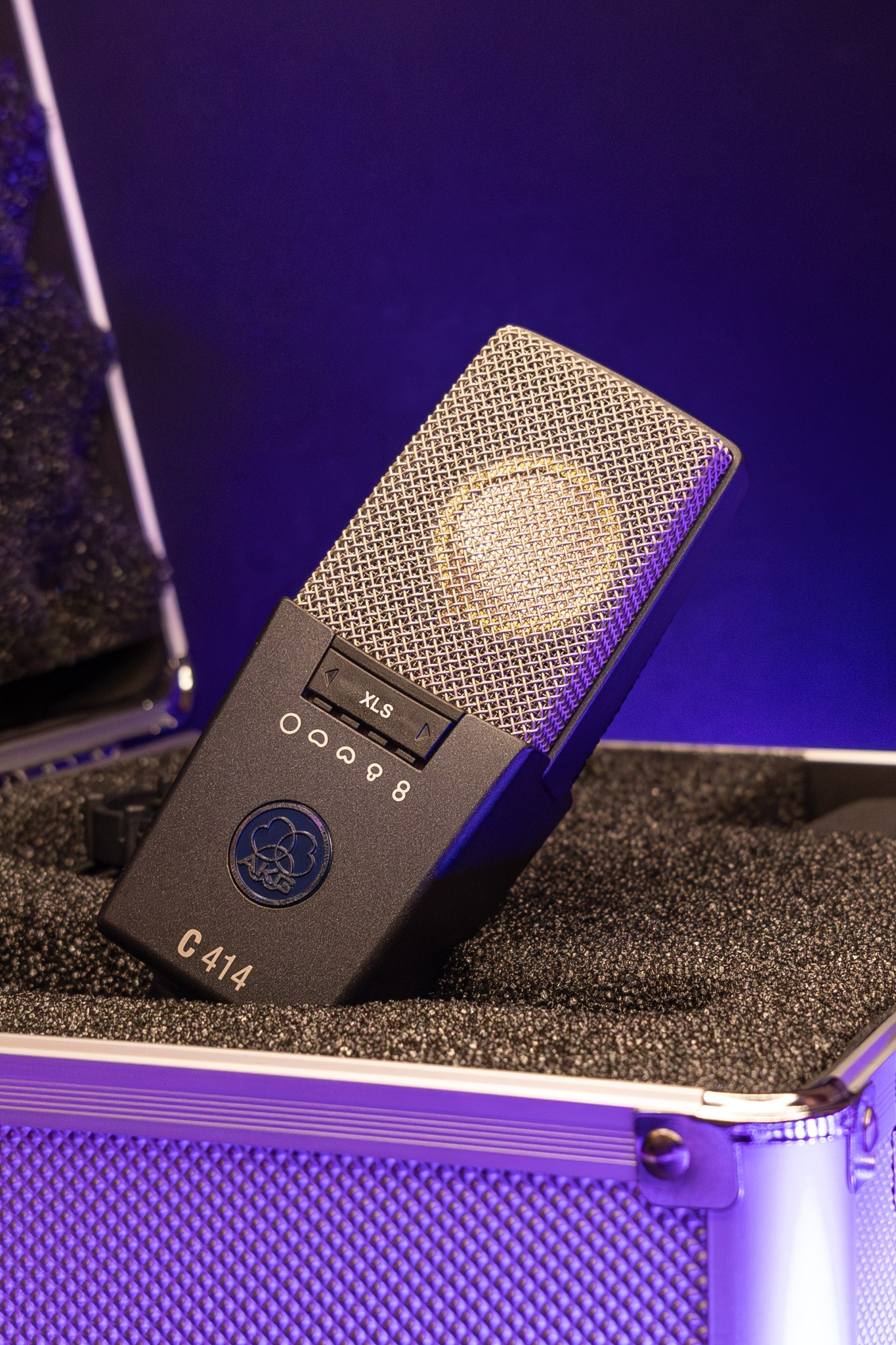 Mikrofon pojemnościowy AKG C414 XLS w twardym futerale, oświetlony fioletowym światłem, widoczne ustawienia charakterystyki kierunkowej.