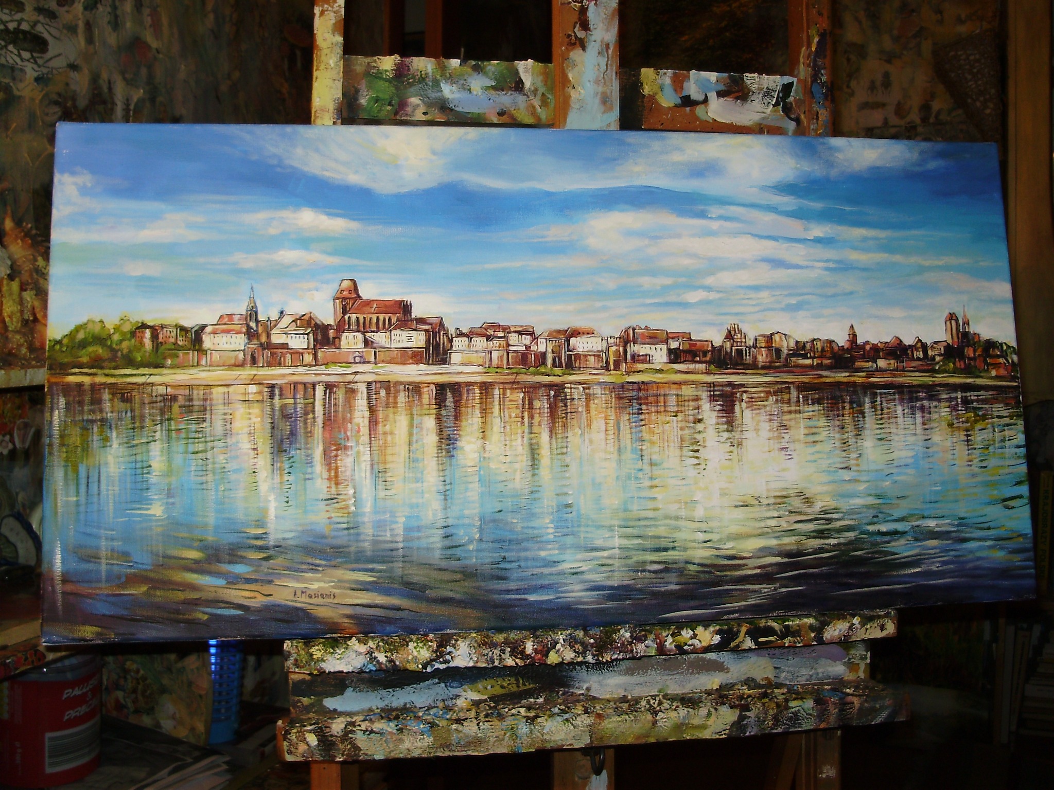 Pejzaż miejski odbity w wodzie, namalowany farbami olejnymi na płótnie, widoczny na sztaludze w pracowni artysty.
