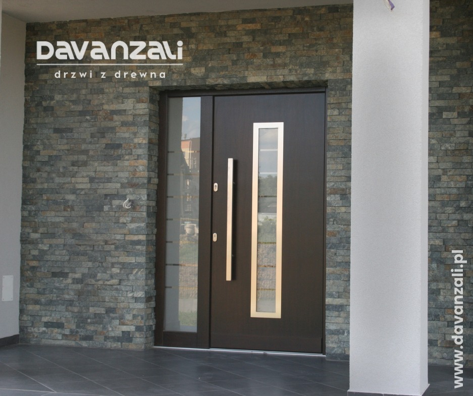 Ciemne drzwi wejściowe z przeszkleniem i długimi, srebrnymi uchwytami, osadzone w kamiennej elewacji. Widoczny fragment kolumny i logo producenta.