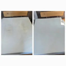 Materac z widoczną różnicą w czystości: po lewej stronie plamy, po prawej czysty, po praniu, na drewnianym stelażu.