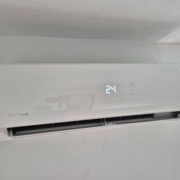 KLIMATCOOL - Biała klimatyzacja Rotenso Ukura Series zamontowana na ścianie, wyświetlająca temperaturę 24 stopnie. Widoczny fragment okna po prawej stronie.