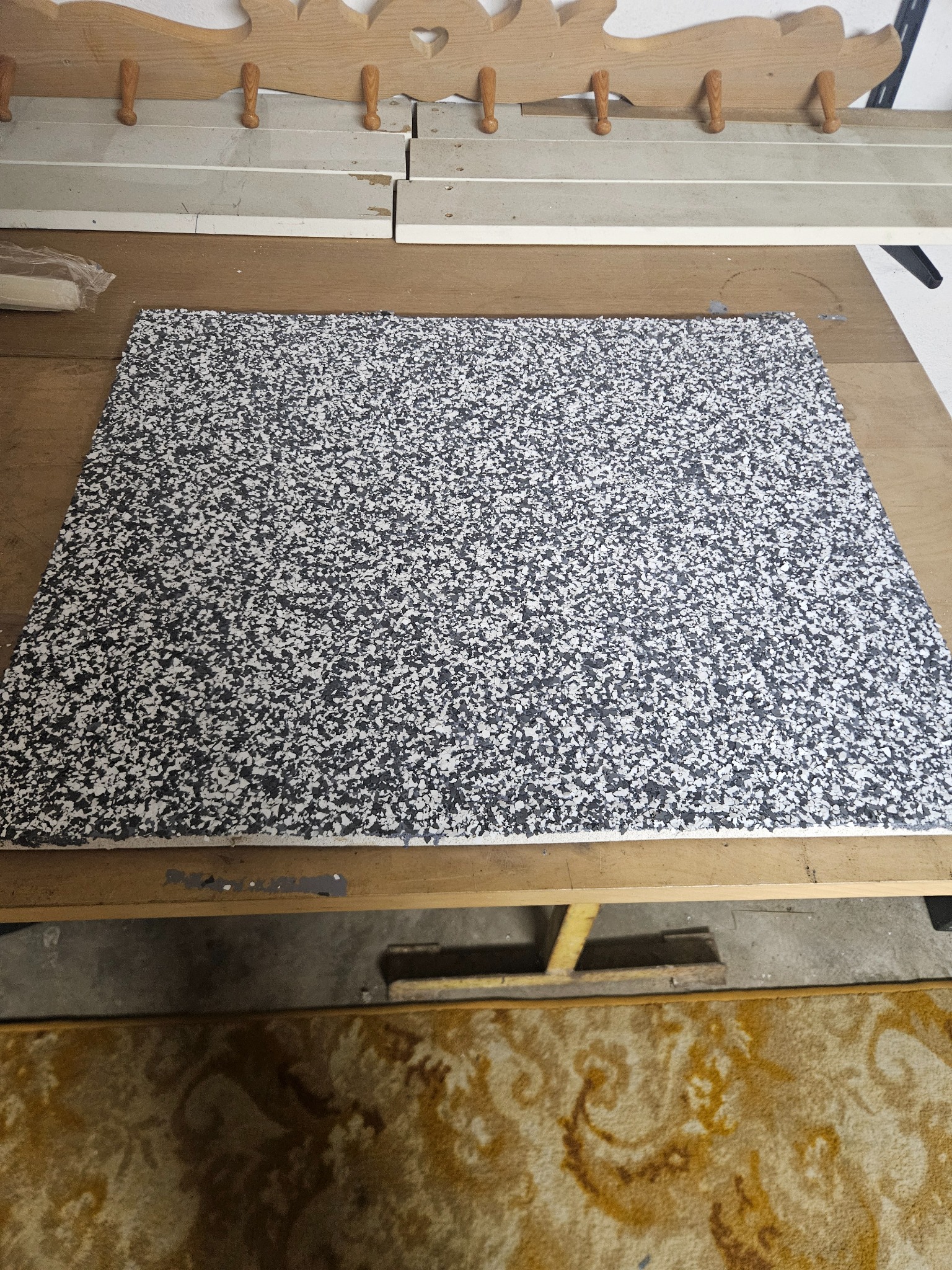 Płyta z wzorem drobnych, nieregularnych czarno-białych plamek leżąca na drewnianym blacie, widoczne elementy warsztatowe w tle.