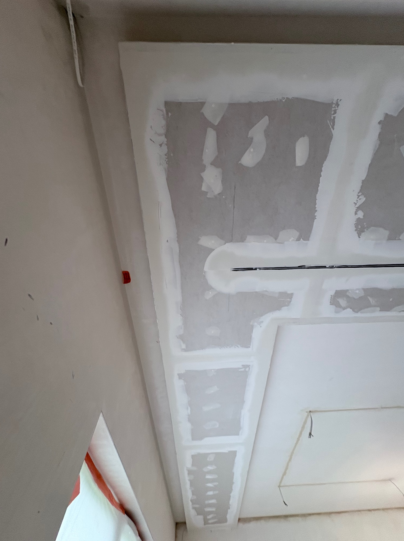 Sufit z płyt kartonowo-gipsowych w trakcie szpachlowania, widoczne łączenia i metalowe profile. Ujęcie pod kątem, surowe wykończenie, przygotowanie do dalszych prac.