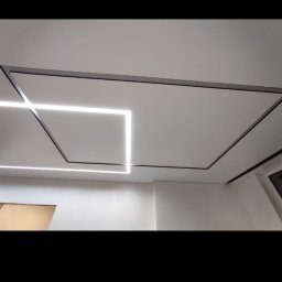 Serhii Holub S-Bud-Rem - Nowoczesny sufit z geometrycznym oświetleniem liniowym w Rybniku, z czarnymi profilami tworzącymi kwadraty i prostokąty na białym tle.