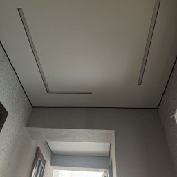 Serhii Holub S-Bud-Rem - Nowoczesny sufit z wpuszczonym oświetleniem liniowym w kształcie litery U, widok z dołu, fragment ściany z oknem w tle.