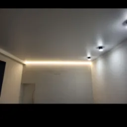 Nowoczesne wnętrze z podwieszonym sufitem z oświetleniem LED, minimalistyczne czarne lampy sufitowe, ściany o delikatnej fakturze i widoczny fragment wnęki w ścianie.