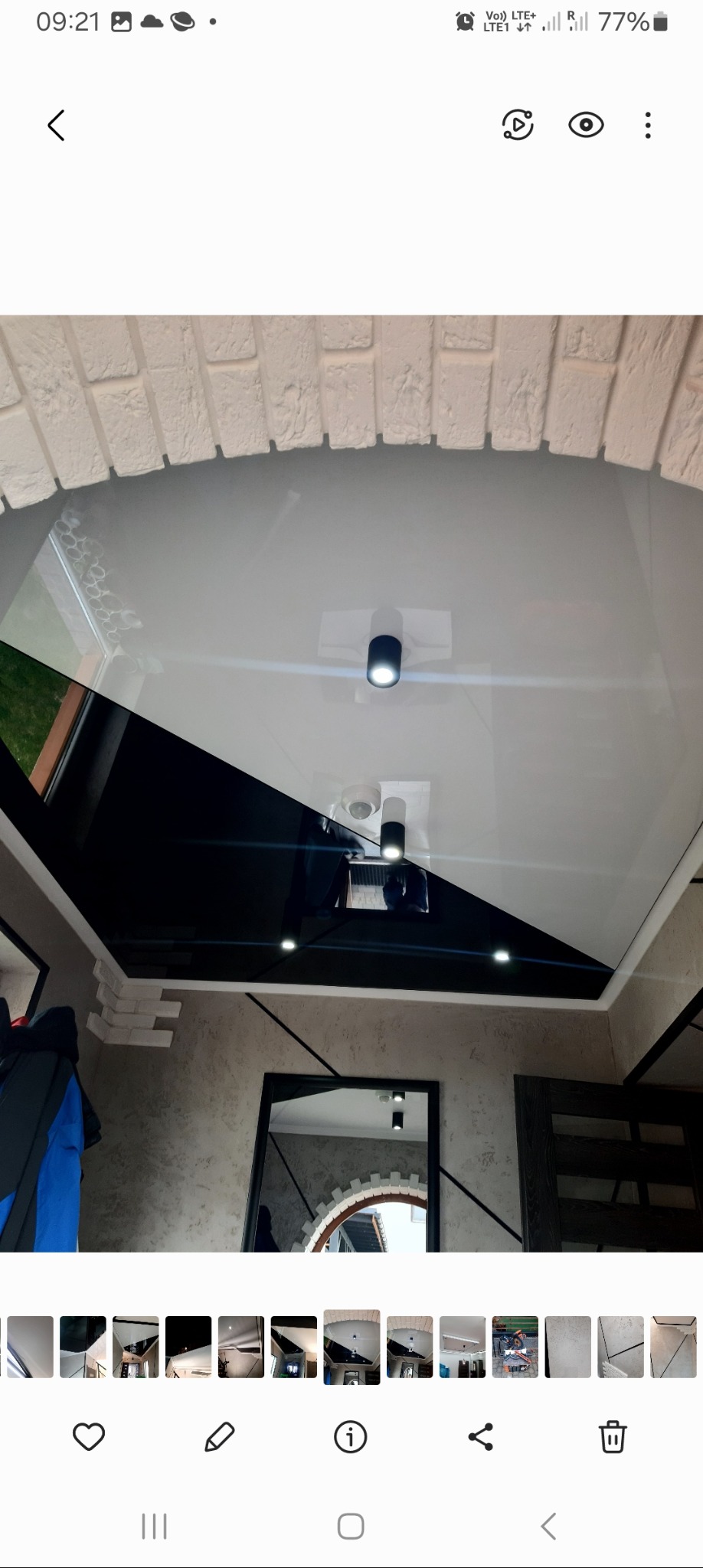 Nowoczesny sufit napinany z czarno-białym podziałem, oświetleniem punktowym i dekoracyjnym łukiem z cegły na ścianie.