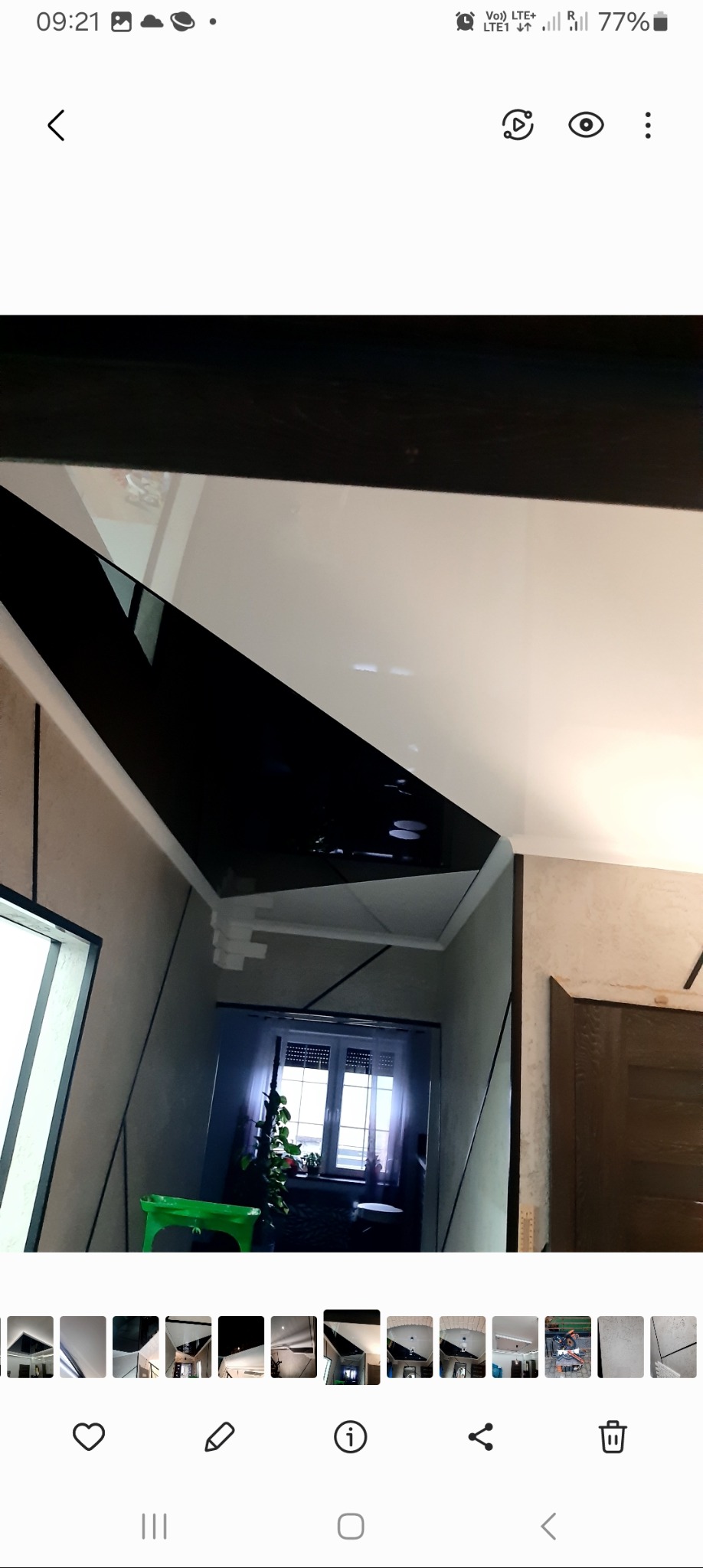 Nowoczesny sufit napinany z czarnym lustrzanym panelem w korytarzu, widok z dołu, z elementami dekoracyjnymi na ścianach i oknem w tle.