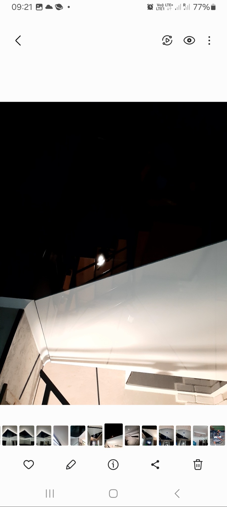 Nowoczesny sufit napinany z białym wykończeniem i ukrytym oświetleniem LED, widoczne odbicie lampy sufitowej.