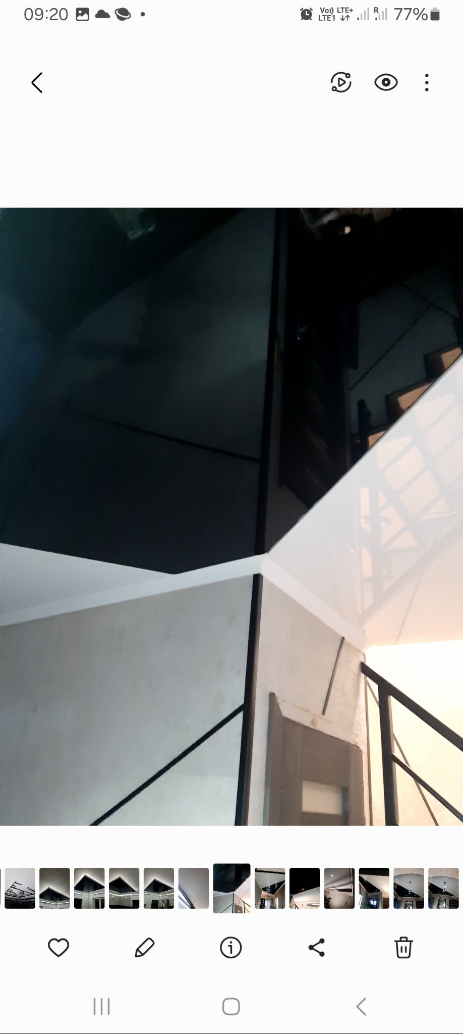 Nowoczesny sufit z czarnymi i białymi panelami, widok z dołu na klatkę schodową z metalową balustradą.