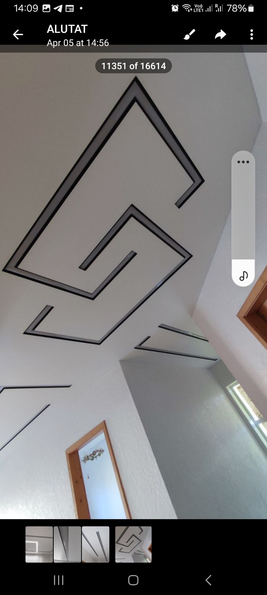 Biały sufit z geometrycznym wzorem w postaci czarnych, wpuszczanych linii tworzących labiryntowy układ, widoczne fragmenty ścian i drzwi.