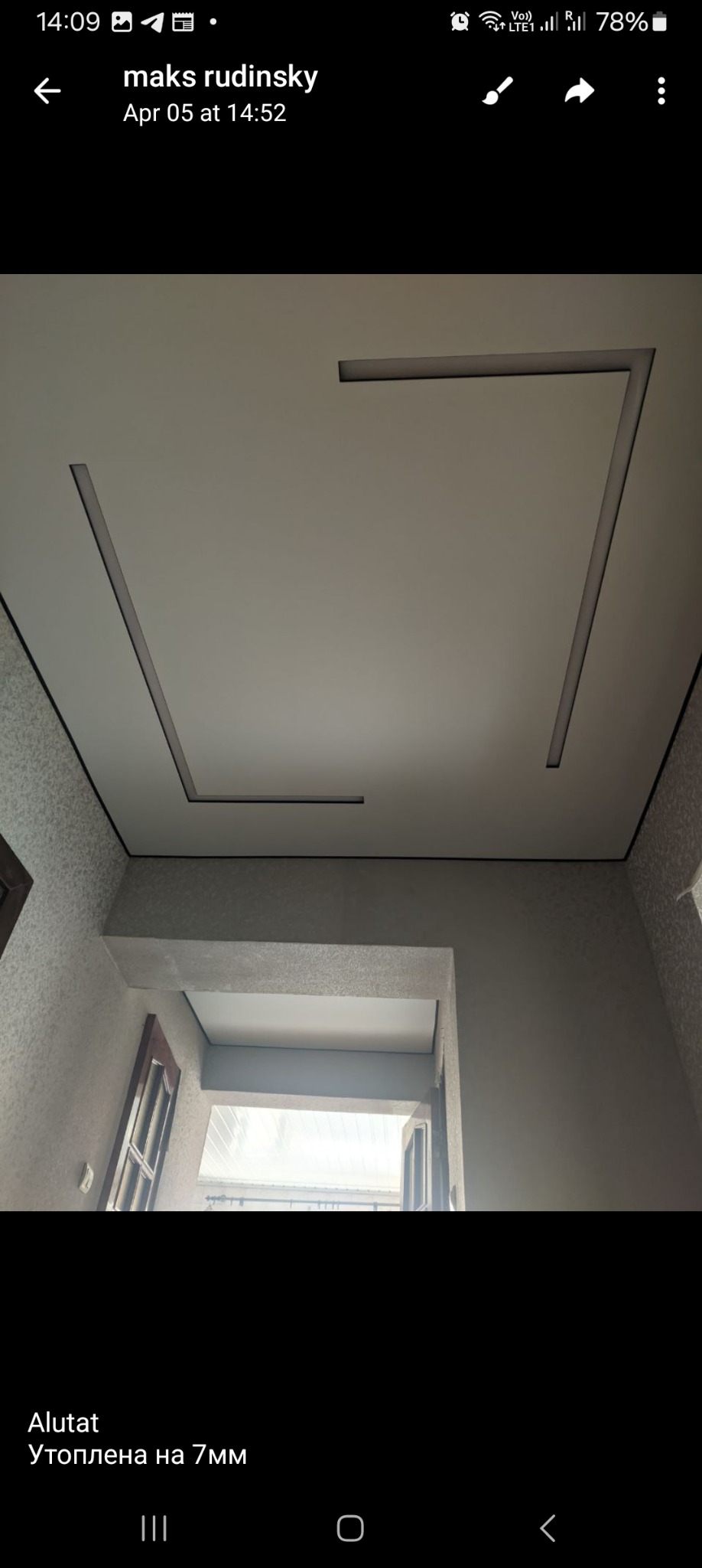 Nowoczesny sufit z wpuszczonym oświetleniem liniowym w kształcie litery U, widok z dołu, fragment ściany z oknem w tle.