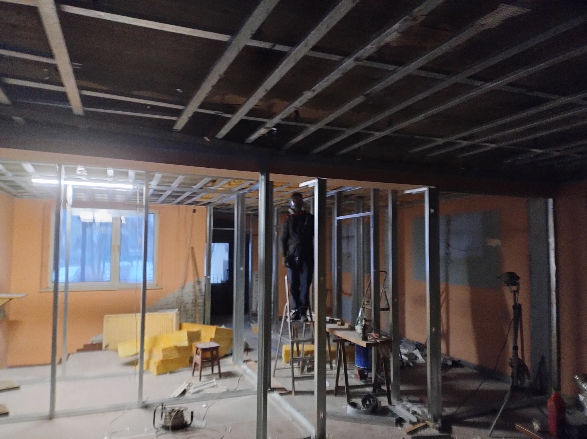 Remont mieszkania: montaż metalowej konstrukcji ścian działowych, widoczne materiały izolacyjne i narzędzia. Prace w toku, surowy stan.