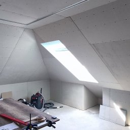 RENOWEJT Przemysław Saniewski - Poddasze z oknem dachowym wykończone płytami kartonowo-gipsowymi, widoczny stół roboczy z narzędziami i odkurzacz przemysłowy.