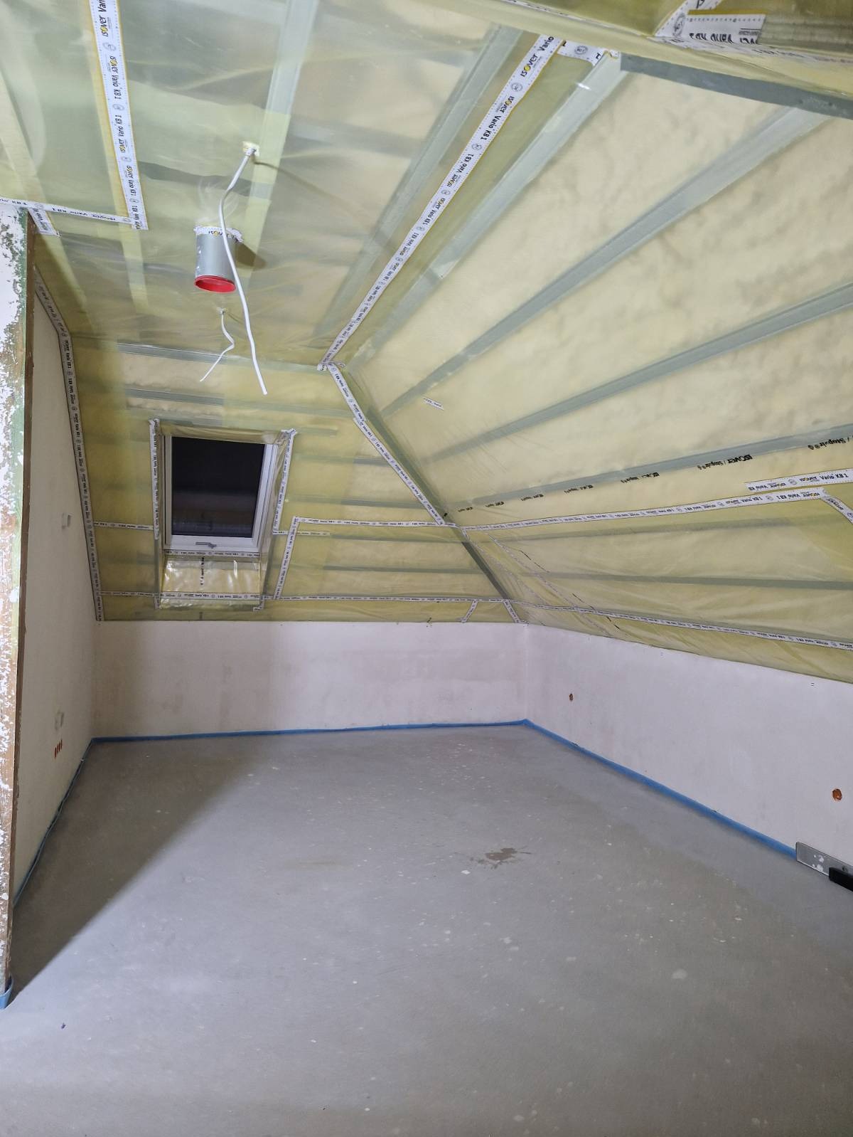 Poddasze w trakcie ocieplania, widoczne folie paroizolacyjne z taśmami uszczelniającymi, metalowe profile, okno dachowe oraz przygotowane ściany do dalszych prac wykończeniowych.