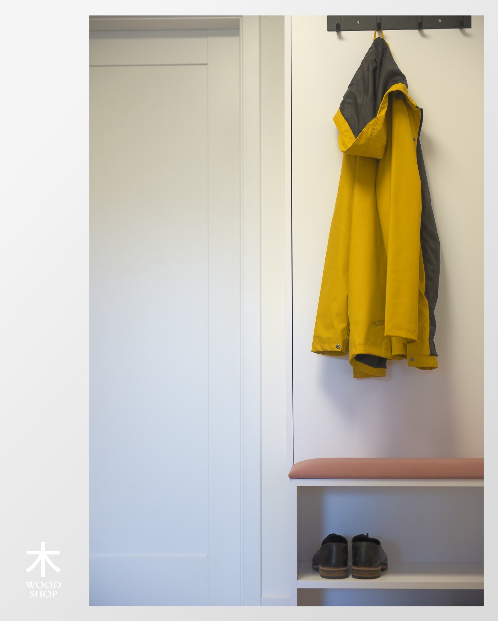 Biała szafa wnękowa z siedziskiem i wieszakiem na kurtkę, obok białe drzwi. Minimalistyczny design, jasne wnętrze, widoczne buty na półce.