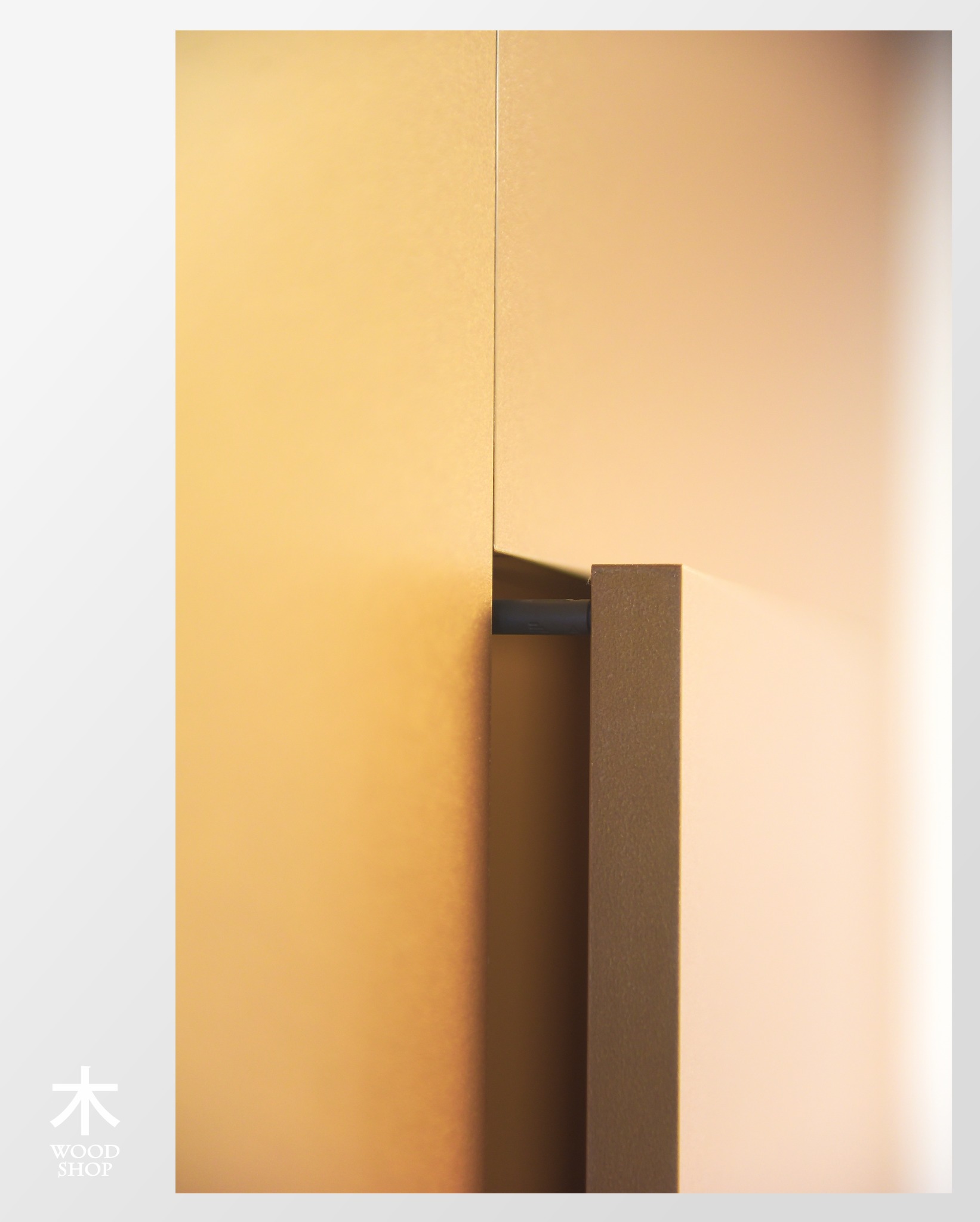 Minimalistyczny detal szafy: złote fronty z ukrytym uchwytem, podkreślone subtelnym światłem, tworzą elegancką i nowoczesną kompozycję.