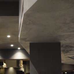 NSB BUILD sp. z o.o. - Nowoczesne wnętrze z ciemnoszarymi ścianami i sufitem o teksturze betonu architektonicznego, podkreślone liniowym oświetleniem LED i punktowymi reflektorami.