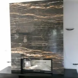 Nowoczesny kominek z obudową z czarnego kamienia z unikalnym, złotym żyłkowaniem, wkomponowany w jasne wnętrze. Minimalistyczny design z dbałością o detale.