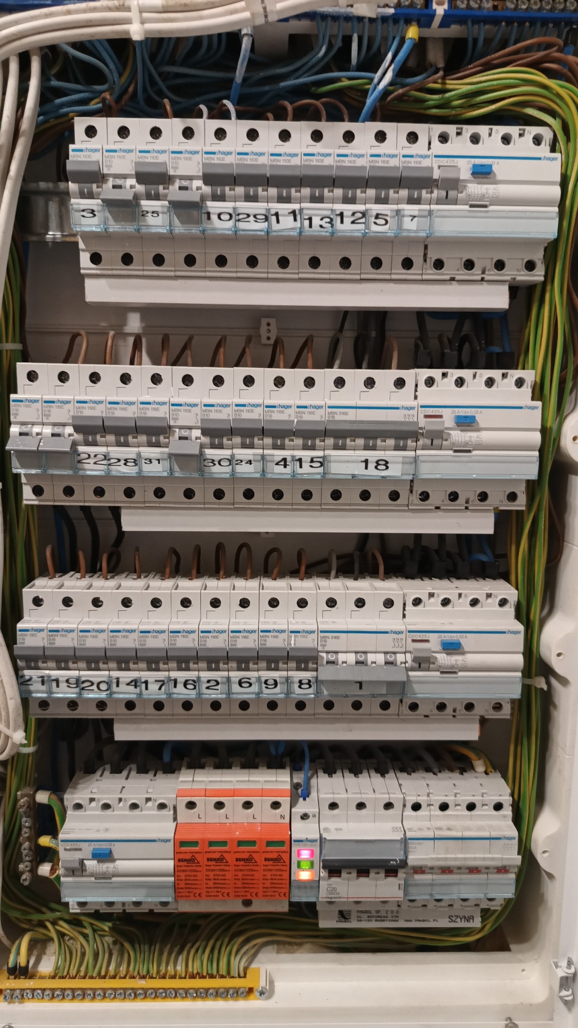 Rozdzielnia elektryczna Hager z bezpiecznikami, widoczne przewody i listwy zaciskowe. Bezpieczniki opisane numerami, część wyłączników w pozycji 'włączone'.