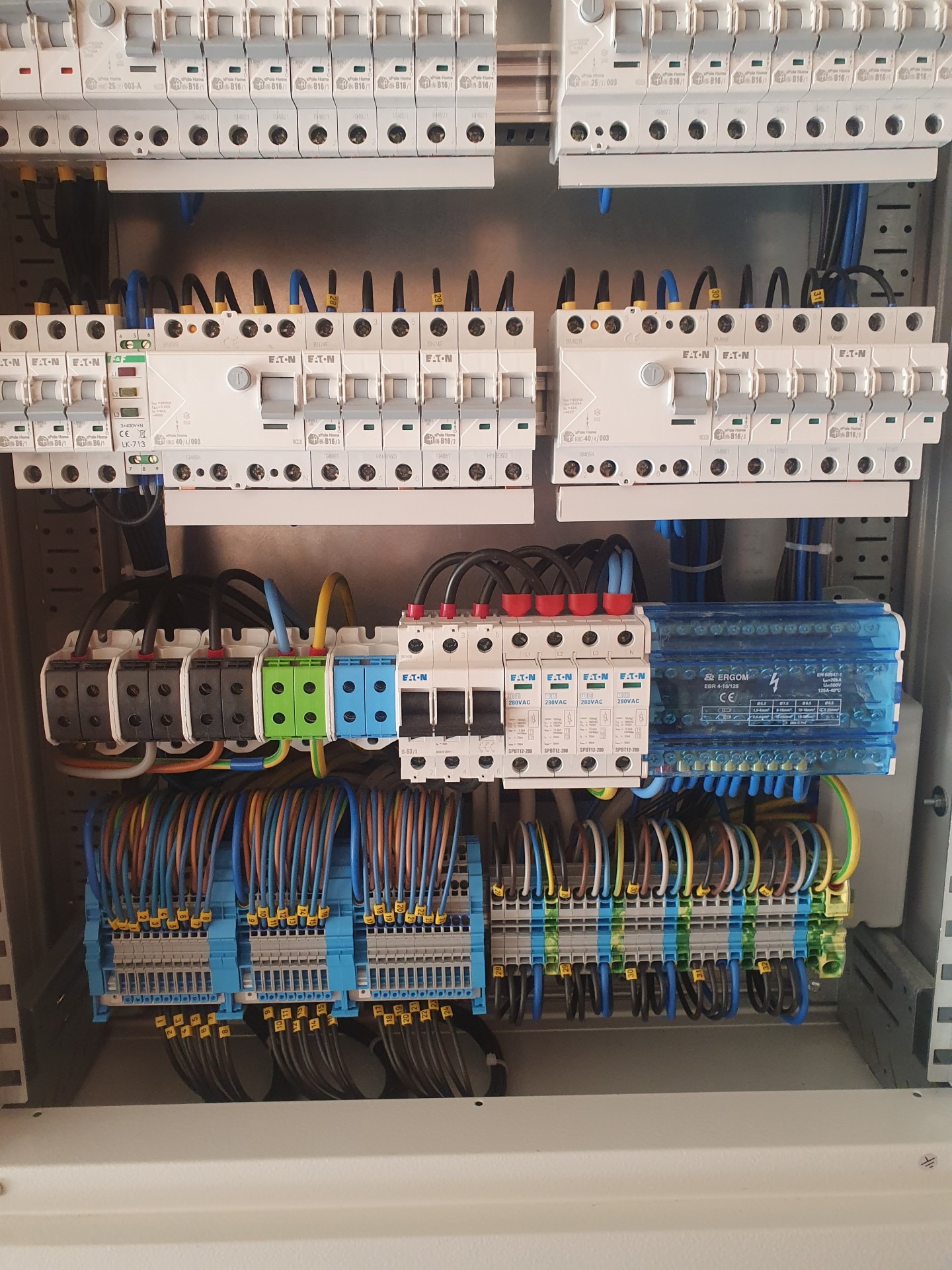 Rozdzielnica elektryczna z precyzyjnie ułożonymi kablami i zabezpieczeniami, widok z bliska na uporządkowane połączenia i komponenty.