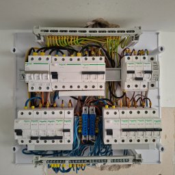 Robo Elektroinstalacje - Starannie wykonana instalacja w otwartej rozdzielnicy elektrycznej Schneider Electric, z rzędami wyłączników i kolorowymi przewodami podłączonymi do listew.