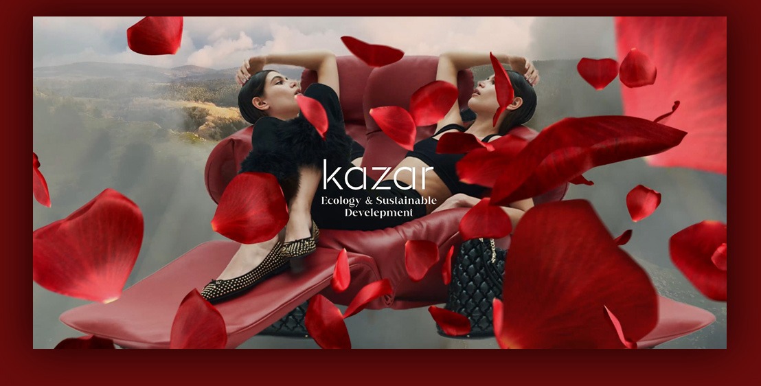 Dwie modelki leżą na czerwonym leżaku na tle górskiego krajobrazu, otoczone opadającymi płatkami czerwonych róż, logo firmy Kazar z napisem Ecology & Sustainable Development.