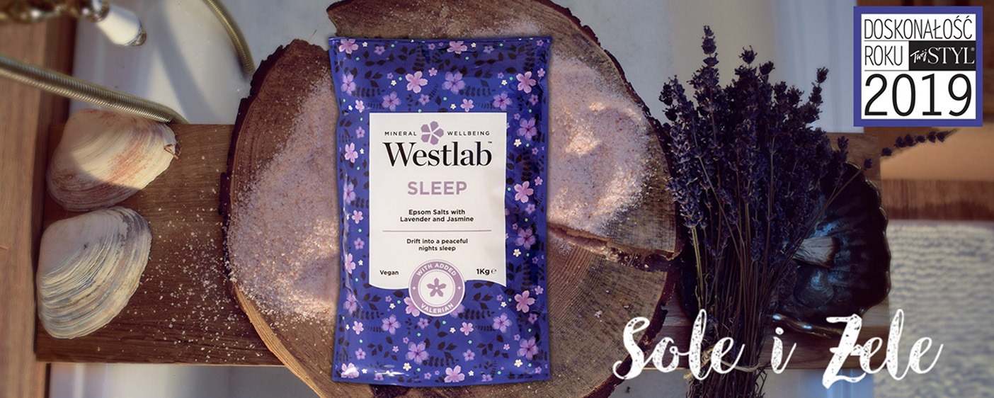 Opakowanie soli Epsom Westlab Sleep z lawendą i jaśminem, ułożone na drewnianym plastrze obok muszli i bukietu lawendy, z nagrodą Doskonałość Roku Twój STYL 2019 w tle.