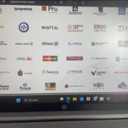 Ekran laptopa z widocznymi logotypami firm finansowych, w tym leasingowych i bankowych, wyświetlanych w przeglądarce. Widoczny pasek zadań systemu Windows.