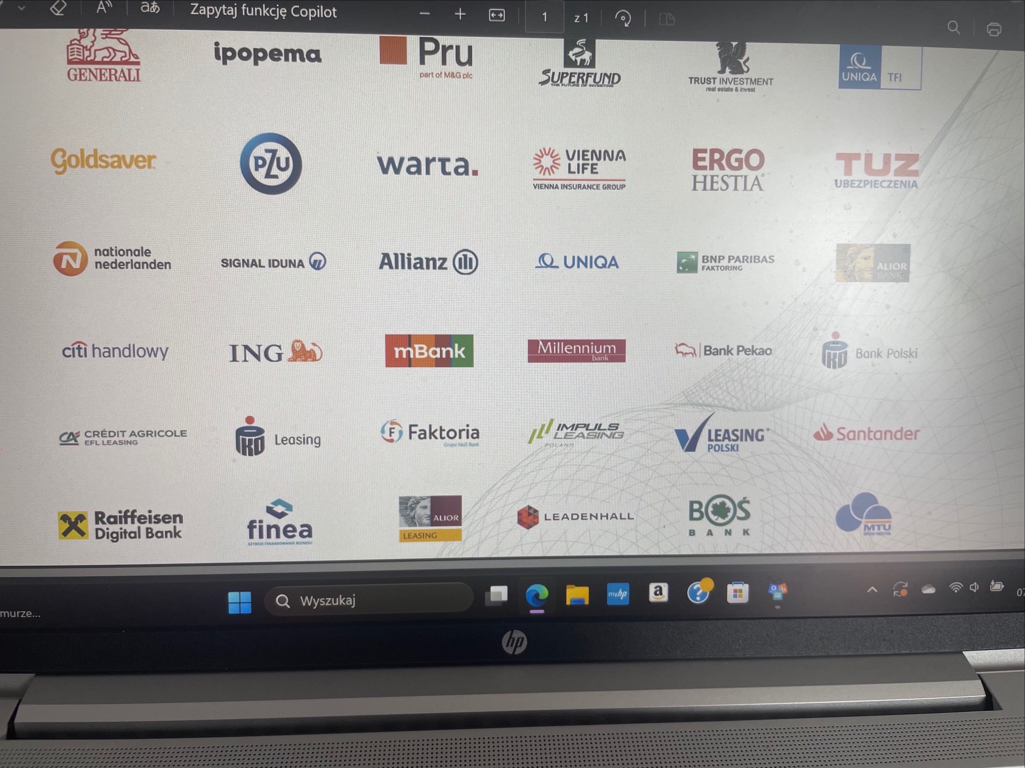 Ekran laptopa z widocznymi logotypami firm finansowych, w tym leasingowych i bankowych, wyświetlanych w przeglądarce. Widoczny pasek zadań systemu Windows.