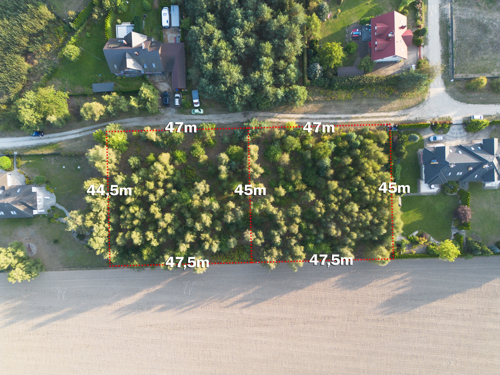 Zdjęcie z drona działki budowlanej z zaznaczonymi wymiarami w metrach, otoczonej drzewami i domami.