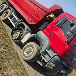 Mobilna wulkanizacja płock 24h7 Paradowski Marcin - Czerwona wywrotka MAN TGA 41.440 na poboczu drogi, z podniesioną skrzynią i widocznymi tablicami rejestracyjnymi.