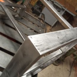 Steel and wood - Metalowa konstrukcja ramy, prawdopodobnie elementu mebla, spawana i częściowo obrobiona, widoczna w warsztacie.