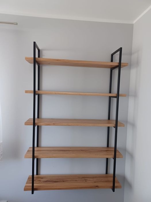 Półka wisząca z drewnianymi blatami i czarnymi metalowymi wspornikami, minimalistyczny design na tle szarej ściany. Widoczne detale faktury drewna.