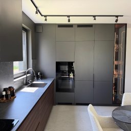 Dmytro Tytorenko - Nowoczesna kuchnia w odcieniach szarości z drewnianymi akcentami, oświetleniem punktowym i przeszkloną witryną na wino. Minimalistyczny design z blatem imitującym kamień.