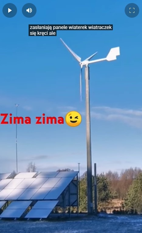 Zimowy krajobraz z turbiną wiatrową i panelami słonecznymi pod błękitnym niebem. Turbina z trzema łopatami. Część paneli pokryta śniegiem.