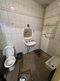 Zaniedbana łazienka przed odświeżeniem w Myszkowie: brudna podłoga, stara umywalka z lustrem, toaleta. Widoczne ślady użytkowania i brak czystości.