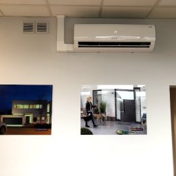 FRIGOPARTNER Bogdan Kobyliński - Biała klimatyzacja ścienna z wyświetlaczem temperatury 17 stopni, zamontowana na ścianie nad dwoma obrazami reklamowymi firmy Hormann.