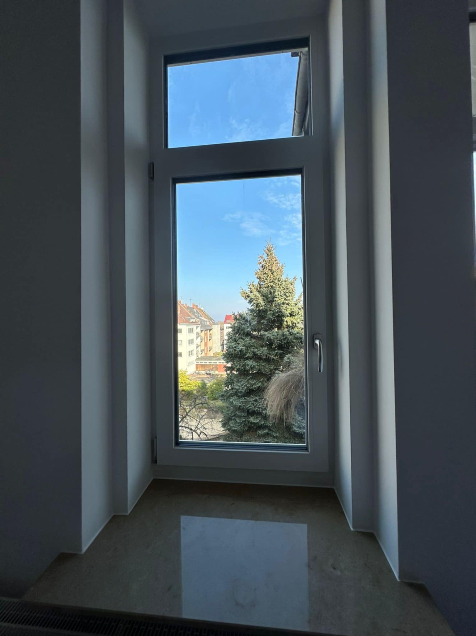 Jasny parapet z kamienia wnęki okiennej z widokiem na zieleń i błękitne niebo w tle, w minimalistycznym wnętrzu. Wykończenie detali.