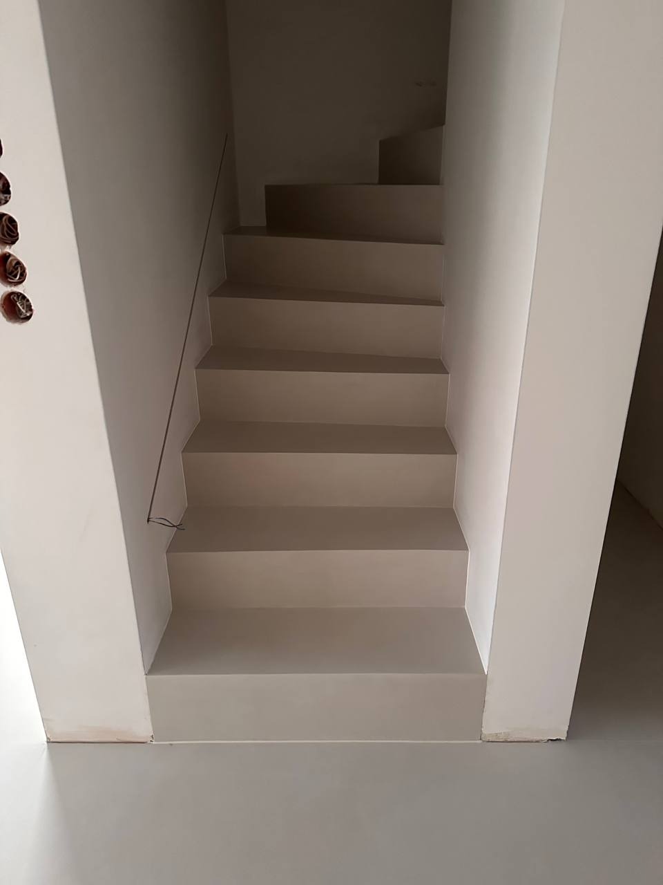 Schody wewnętrzne po wyrównaniu ścian i stopni, widoczne puszki elektryczne bez osprzętu po lewej stronie.