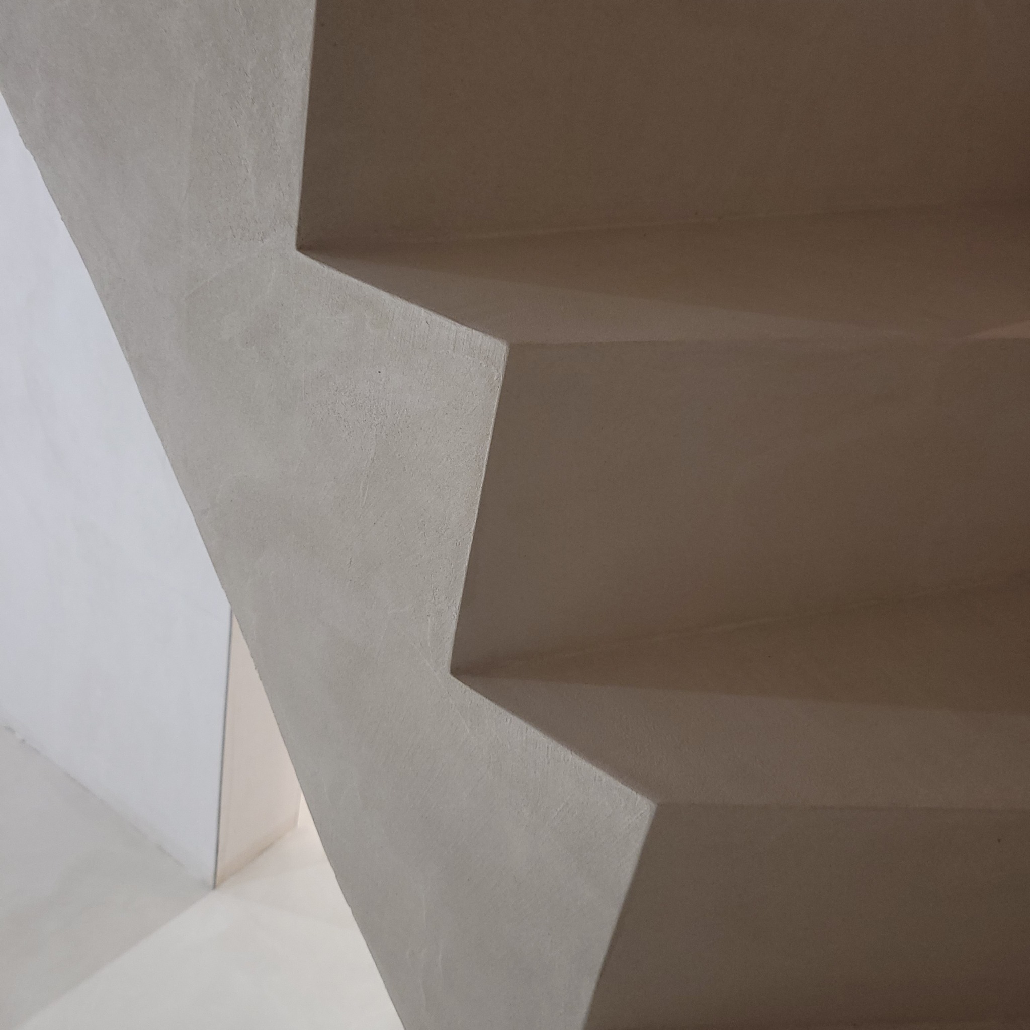 Schody wewnętrzne wykończone mikrocementem w odcieniach szarości, z widoczną strukturą materiału i minimalistycznym designem.