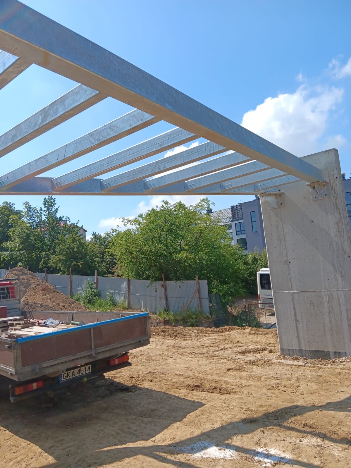 Konstrukcja stalowa z profili ocynkowanych, zamontowana na betonowym słupie, widoczna w trakcie budowy na tle nieba i zieleni.