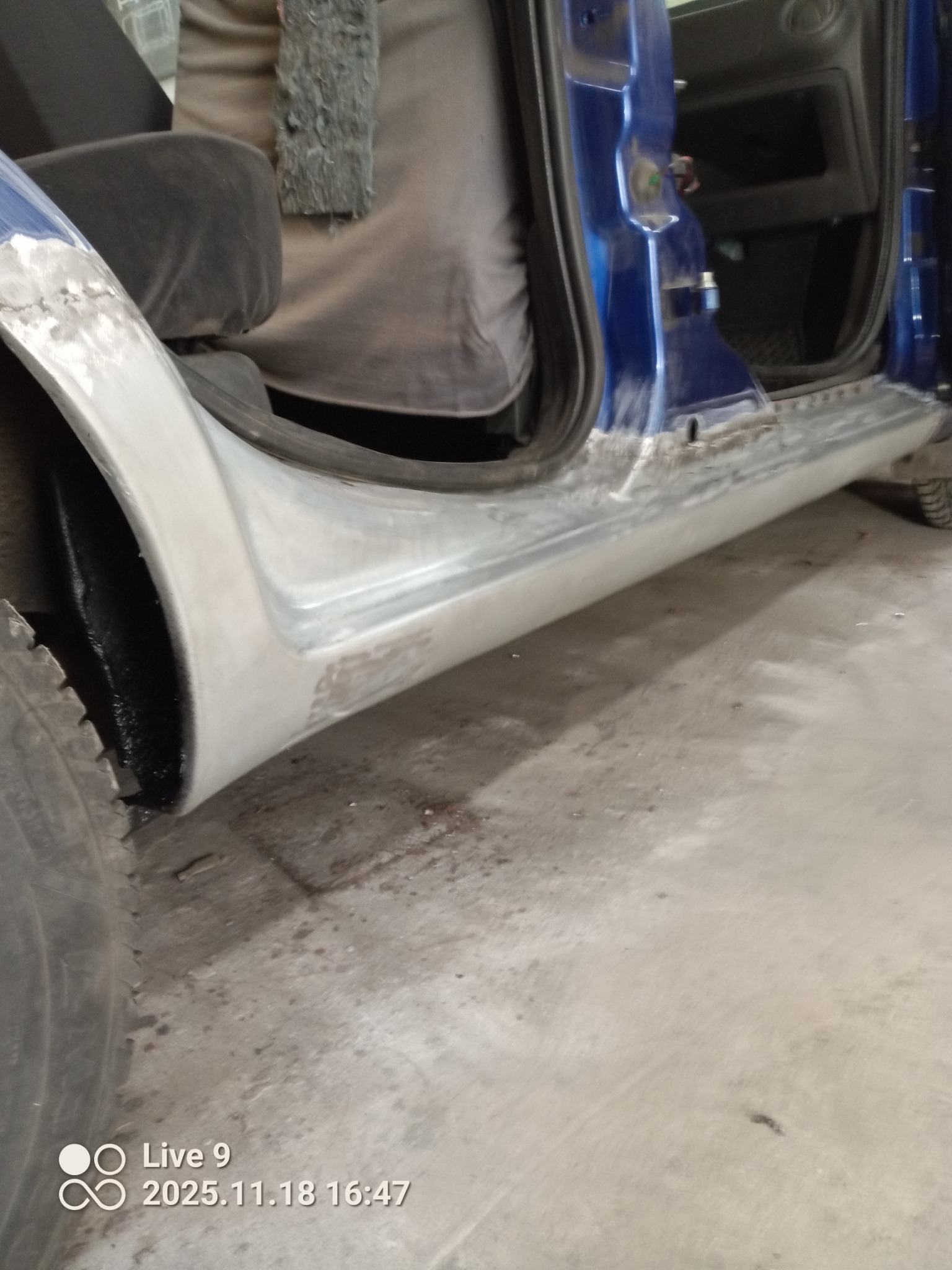 Niebieski samochód w trakcie naprawy blacharskiej, widoczne szpachlowane progi i nadkole. Detal z warsztatu, etap przygotowania do lakierowania.