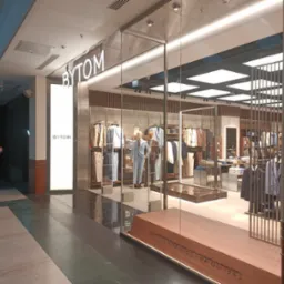 Elegancka witryna sklepu odzieżowego Bytom, obłożona szlifowaną blachą ze stali nierdzewnej AISI304. Widoczny fragment wnętrza sklepu i sylwetka mężczyzny.