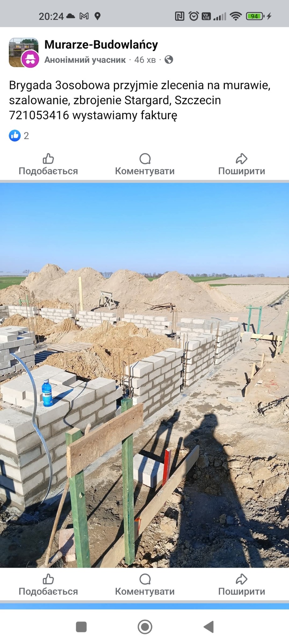 Wznoszenie ścian fundamentowych z bloczków betonowych na placu budowy, widoczne zbrojenia i sterta piasku w tle.