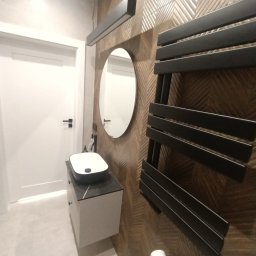 FRB MACIEJ BOROWIAK - Nowoczesna łazienka z umywalką nablatową, lustrem i grzejnikiem drabinkowym na ścianie wyłożonej płytkami w geometryczny wzór. Minimalistyczne oświetlenie.